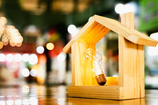 桌子上的木屋灯泡：建筑、创意、能源或商业理念，生态、贷款、抵押、房产或家居的象征图片下载