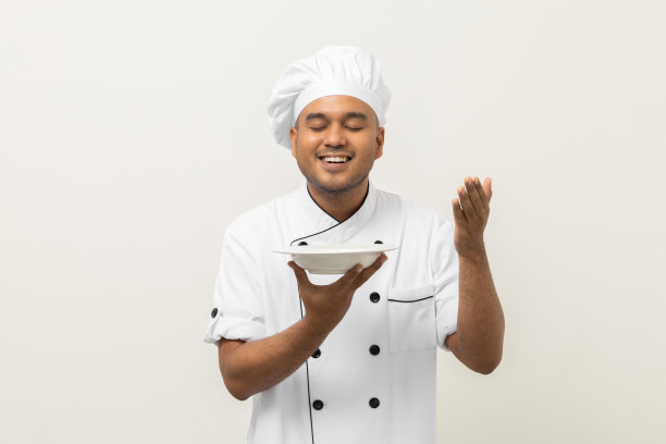 开朗的年轻英俊的亚洲人厨师在统一的姿态闻空盘子美味的菜菜单好味道上孤立。厨师职业:厨房、餐厅、酒店的厨师或面包师。图片下载