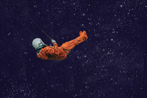 穿着橙色宇航服的宇航员在开阔的空间里荡秋千图片下载