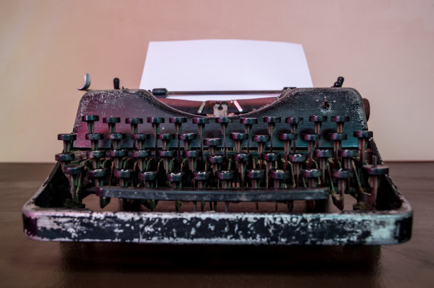 老式打字机和一张白纸放在一张旧办公桌上。图片下载