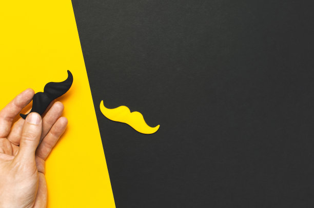 创意派对装饰理念。男性手握黑黄胡子，道具为拍照亭，狂欢节派对上的黑黄背景俯视图平lay父亲节男人的健康意识图片下载