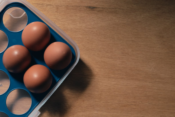 鸡蛋放在盒子里，放在一个木制的背景上。图片下载