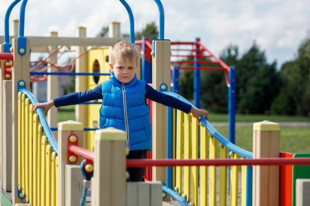 一个穿着蓝色背心的小男孩走在一座波浪形的桥上。图片下载
