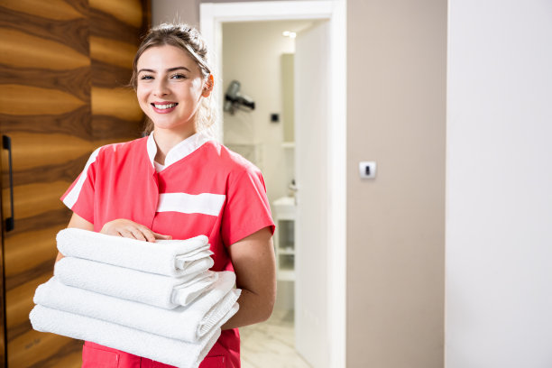 酒店房间里拿着干净毛巾微笑的女仆肖像。图片下载