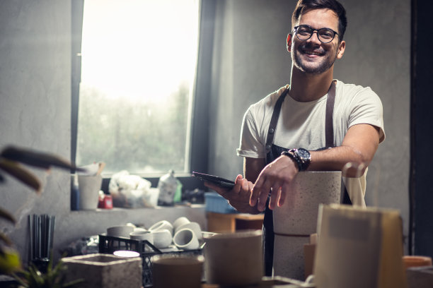 系围裙的工匠在作坊里制作装饰用的混凝土花瓶。图片下载