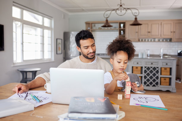 混血小女孩在客厅里做作业，年轻的爸爸在用笔记本电脑工作图片下载