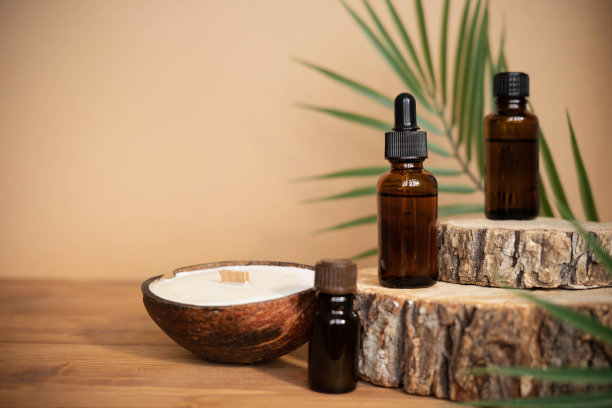 精油装在琥珀色的玻璃瓶里，放在木片上，用棕榈叶和椰子做的蜡烛。紫色的温泉浴场模型。图片下载