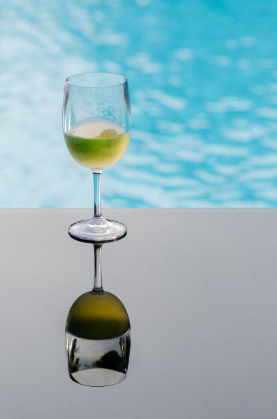 游泳池的桌子上放着一杯白葡萄酒图片下载