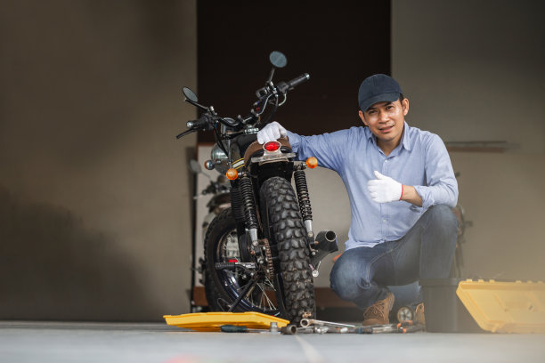 在修理店修理摩托车的快乐的机修工，修理工在车库修理摩托车，修理工修理摩托车发动机素材图片