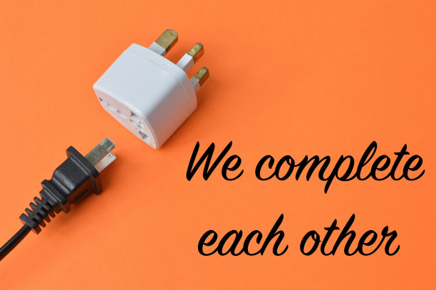 插座和插头在橙色背景上写着WE完成彼此。图片下载