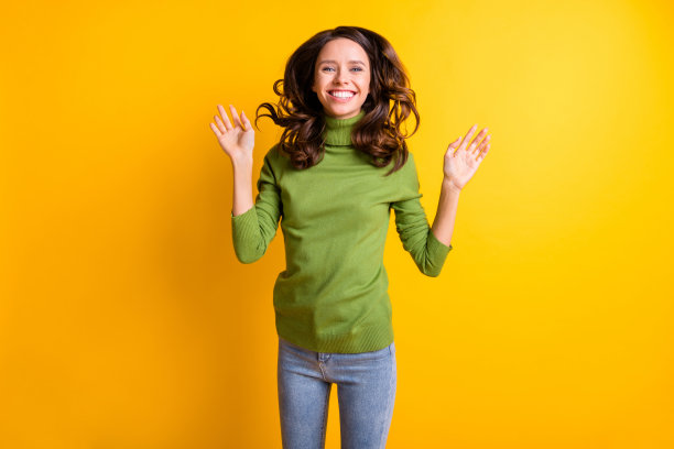 年轻快乐的照片微笑开朗的好心情的女人显示手掌与飞扬的头发孤立在黄色背景图片下载