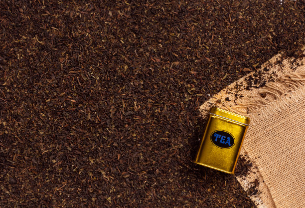 金色茶盒上的干红茶叶背景与粗麻布，茶店的概念图片下载