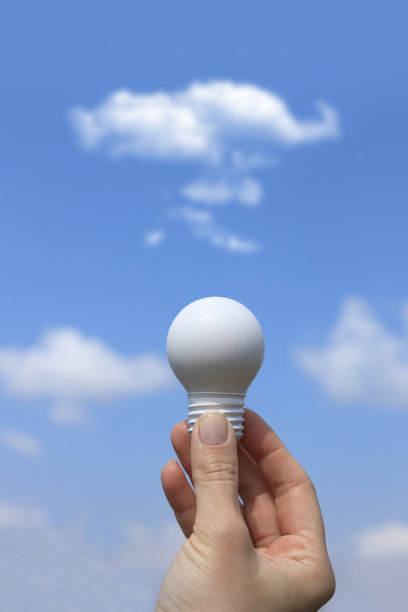 女人的手拿着一个白色的灯泡，对着蓝天图片下载