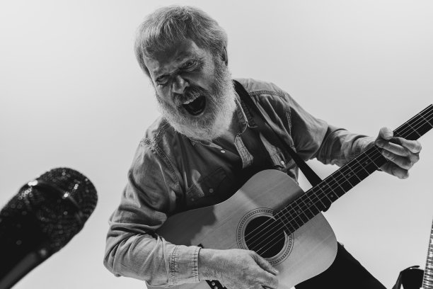 黑白肖像的时尚老人，摇滚音乐家在音乐工作室室内演奏吉他。排练基地的艺术概念、音乐、风格、老一代、复古图片下载