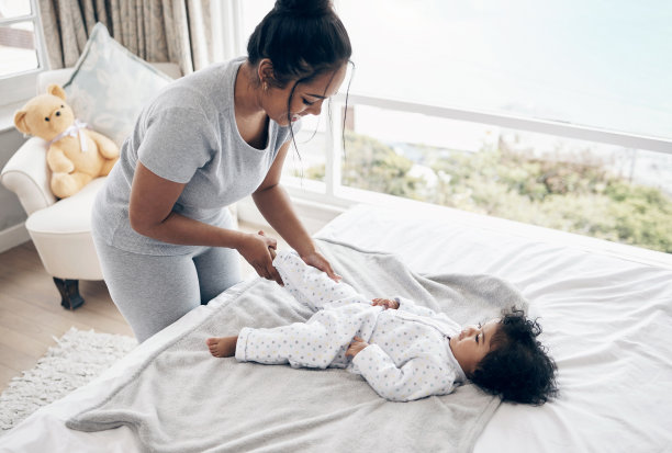 一位年轻的母亲在家里给她的女儿换尿布图片下载