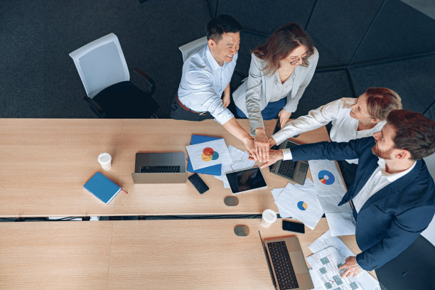 在办公室里，形形色色的商务人士站在桌子旁时，总是手拉手图片下载