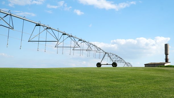 园地及灌溉设备。轮式洒水车灌溉肥沃的农田。灌溉植物用于灌溉绿色作物。概念:农业或供水。图片下载