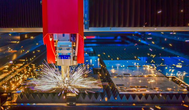 工业激光切割机在火花灯下切割金属板材。图片下载