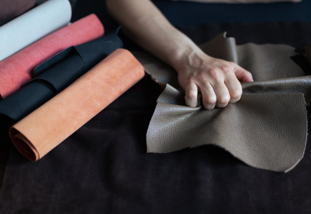 一位专业的工匠，坐在他的办公桌前，挑选一卷牛皮，用来制作皮革制品图片下载