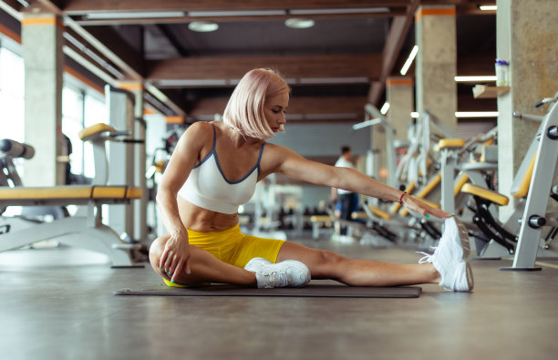 年轻的女运动员在健身房的垫子上练习体操。健康的生活方式。健美和健身图片下载