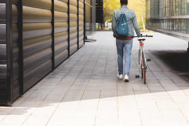 一个年轻人走在他的自行车旁边图片下载