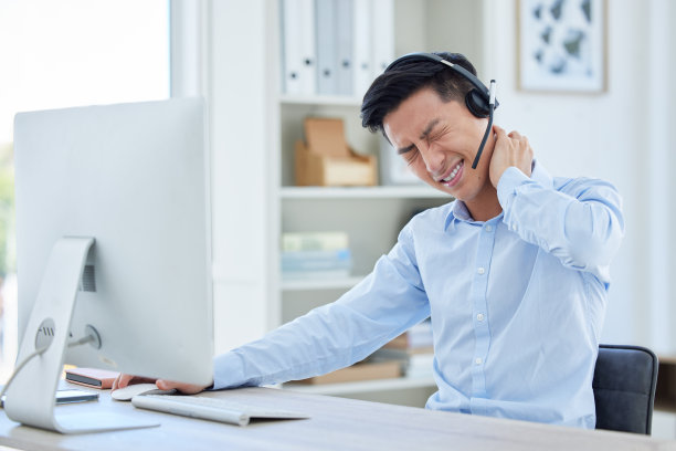 在办公室里因颈椎疼痛而难受的年轻亚洲呼叫中心电话销售代理图片下载