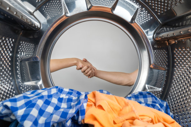 女人和男人的手在洗衣机的滚筒旁紧握在一起握手，从里面拍摄。立下合同，做好工作图片下载