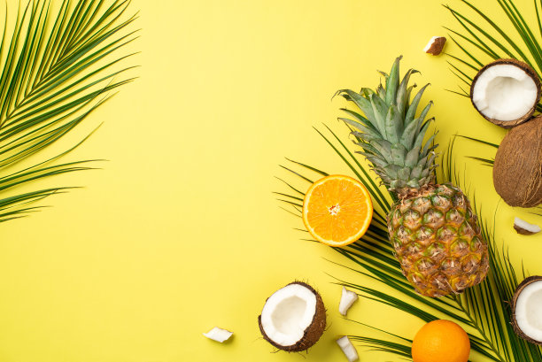 夏天的概念。热带水果的俯视图照片，椰子片菠萝橙一半和棕榈叶在孤立的黄色背景与空白图片下载