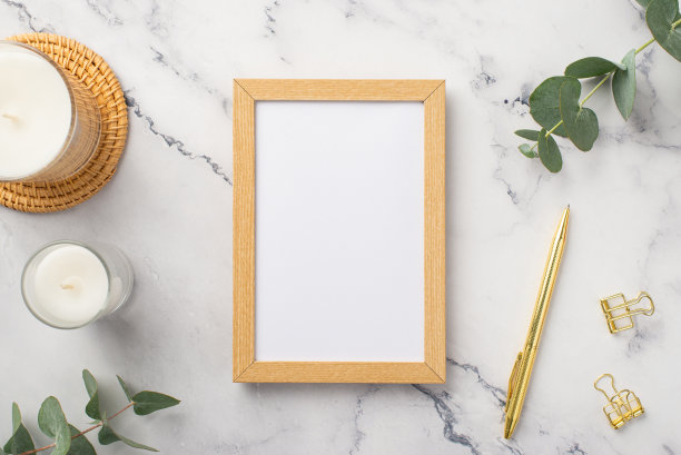 俯视图照片的木制相框蜡烛藤服务垫金笔活页夹和桉树在白色大理石背景与空白图片下载