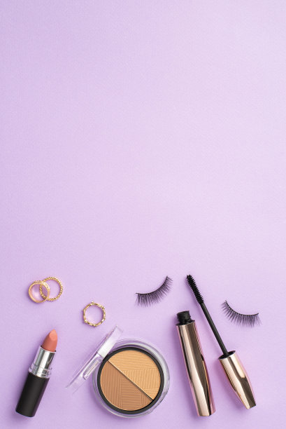 化妆美容的概念。俯视图垂直照片的假睫毛睫毛膏黄金戒指轮廓调色板和口红在孤立的淡紫色背景与copyspace图片下载
