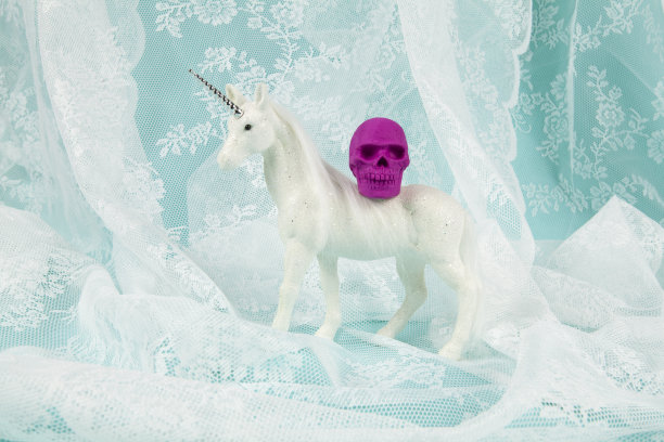 一只闪亮的白色独角兽背上背着一个塑料头骨图片下载