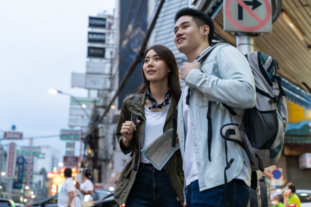 亚洲活跃的年轻夫妇晚上在城市旅行蜜月旅行。迷人的新婚男子和女子背包客走在街上享受花时间约会情人节假期在一起图片下载