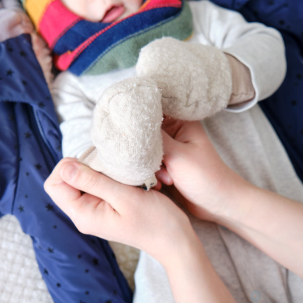 一位母亲给男婴戴上了温暖的连指手套。妈妈在床上给一个快乐的孩子穿上冬天的衣服。图片下载