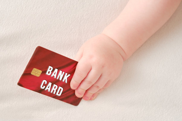 蹒跚学步的小男孩手里拿着一张信用卡。拿着银行卡的孩子，特写图片下载