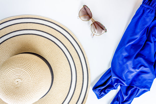 一顶女士柳条帽，上面有一副复古太阳镜，白色背景上的蓝色连衣裙图片下载