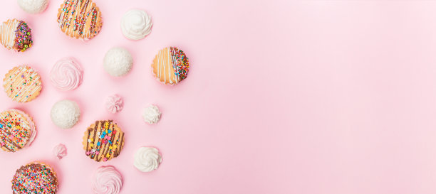 粉红色的背景上放着手工饼干和棉花糖。图片下载
