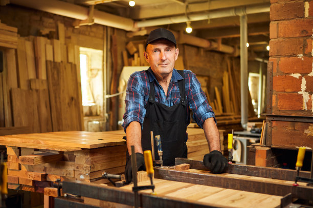肖像高级木匠在均匀胶木棒与手压力在木工制造图片下载