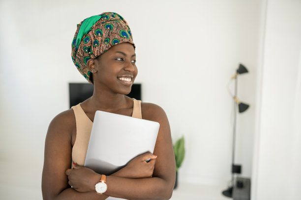 肖像黑人非洲妇女在家里，微笑着拿着笔记本电脑图片下载
