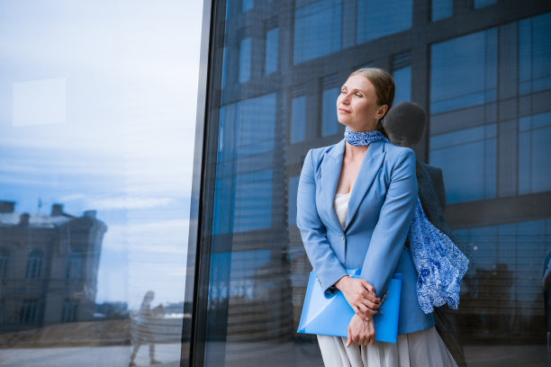 在办公楼附近手拿文件夹的女商人图片下载
