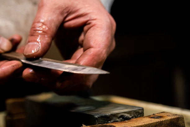 刀匠在磨刀石上用水磨刀图片下载