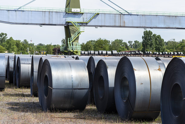 铁轨旁的装货场里，一架起重机矗立着，上面包裹着大卷的金属片。图片下载