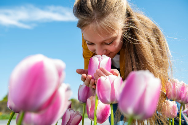 一个美丽的少女正在闻郁金香花。图片下载