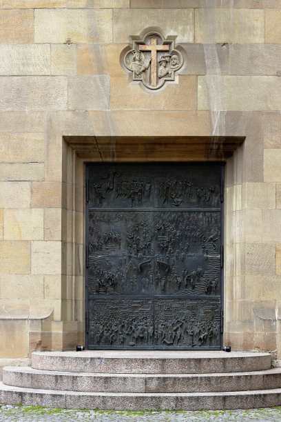 德国斯图加特，一个古老的大教堂外立面的碎片，有伪造的装饰门，石雕十字和入口楼梯。建筑采用石灰石，传统建筑材料。图片下载