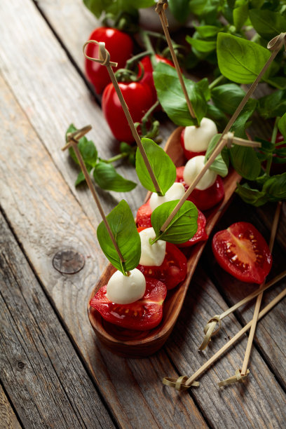 马苏里拉奶酪配罗勒和西红柿放在一张旧木桌上。图片下载