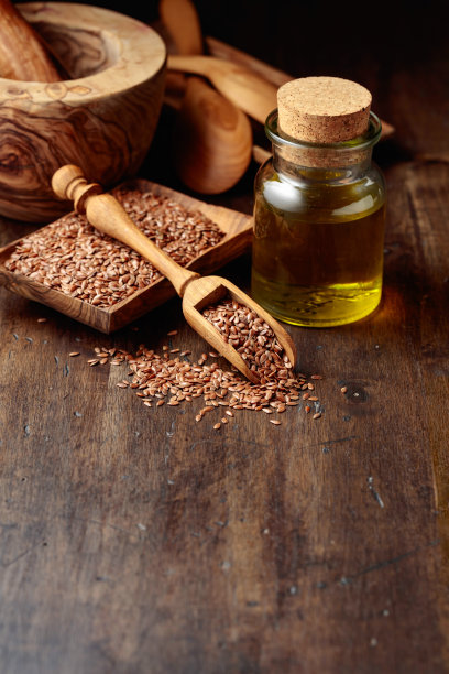一张旧木桌上放着亚麻籽和亚麻籽油。图片下载