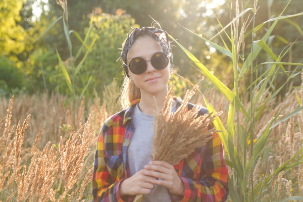 在自然背景下行走的小女孩拿着蒲苇草图片下载