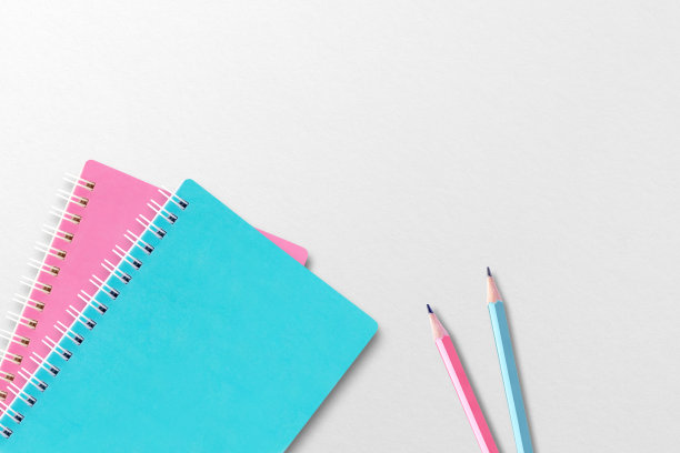 蓝色和粉色的笔记本放在白纸上。两支铅笔。图片下载