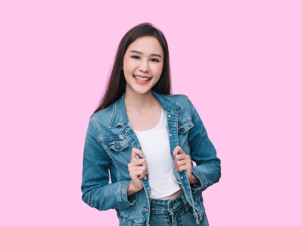 肖像微笑开朗的年轻亚洲妇女在牛仔裤裙，快乐积极的情绪，孤立在粉红色的背景图片下载