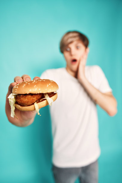 非常饥饿的年轻人拿着美味的汉堡图片下载