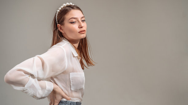 背部疼痛，年轻女子站着的时候正承受着腰部疼痛。图片下载